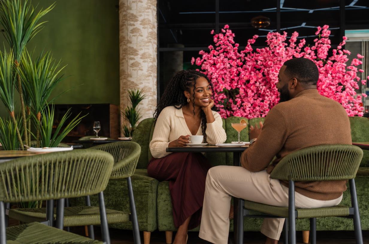 A couple sharing a Sunday afternoon table at Soul, one with a coffee and one with a cocktail, pink blossom behind them